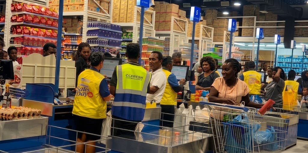 A sales team member serving a customer while Tweaks handles incoming WhatsApp enquiries